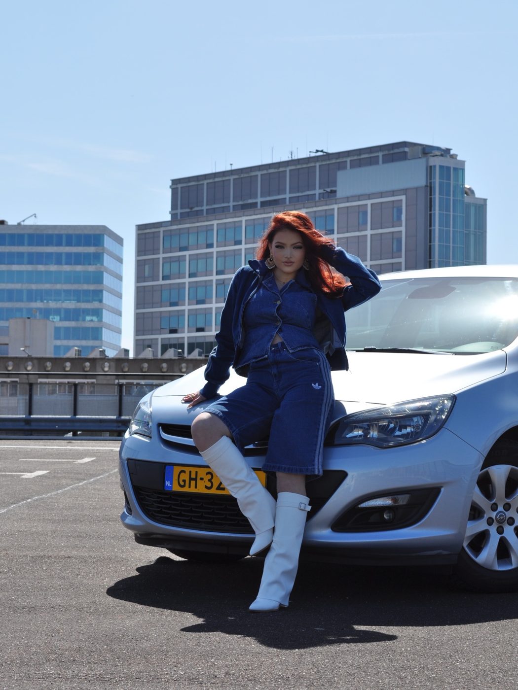 Floor Bartels poseert bij een zilveren Opel Astra op een parkeerdak