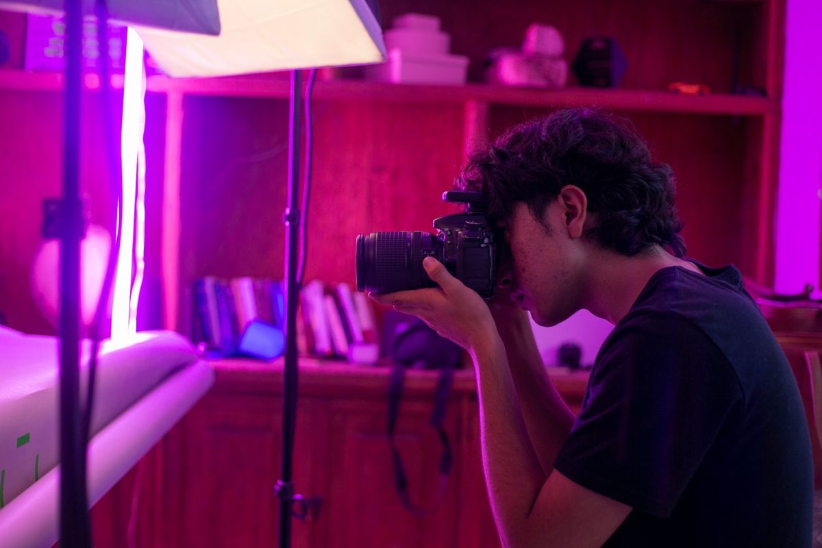 Fotograaf met spiegelreflexcamera in een roze ruimte