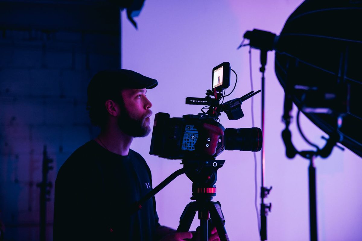 Cameraman achter een filmcamera in blauw-paars licht