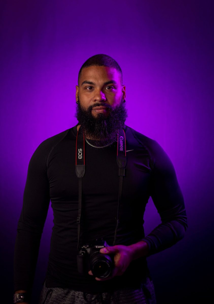 Portret van een man met camera tegen een paarse achtergrond