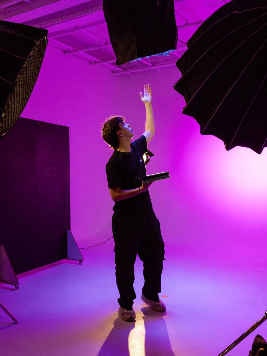 Fotograaf zet licht klaar in een paarse studio