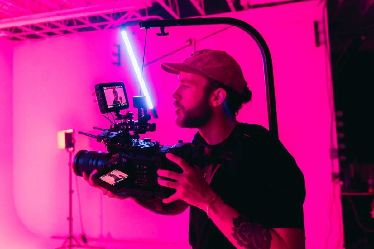 Videograaf met filmcamera in roze licht